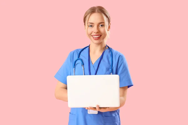 ピンクの背景にラップトップを使用した女性医療インターン — ストック写真