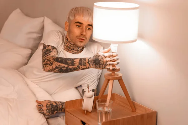 Fiatal Tetovált Férfi Kikapcsolja Lámpát Ágyban Éjszaka — Stock Fotó