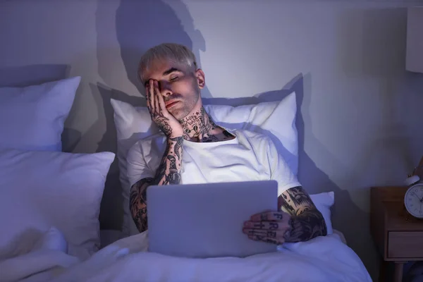 Sömnig Ung Tatuerad Man Med Laptop Sängen Natten — Stockfoto