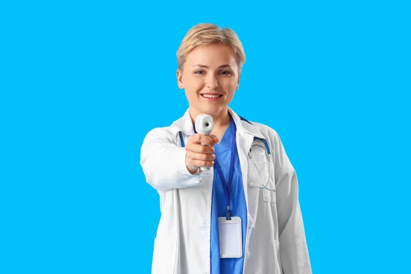 Vrouwelijke Medische Stagiaire Met Infrarood Thermometer Blauwe Achtergrond — Stockfoto