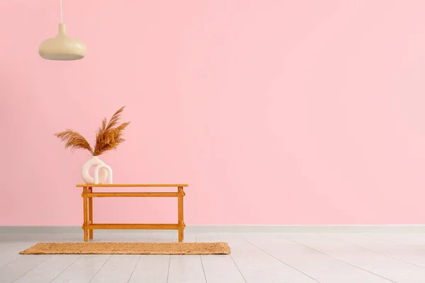 ピンクの壁の近くの花瓶にパンパス草と木製のテーブル — ストック写真