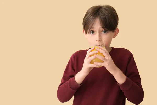 Mały Chłopiec Pijący Sok Pomarańczowy Beżowym Tle — Zdjęcie stockowe