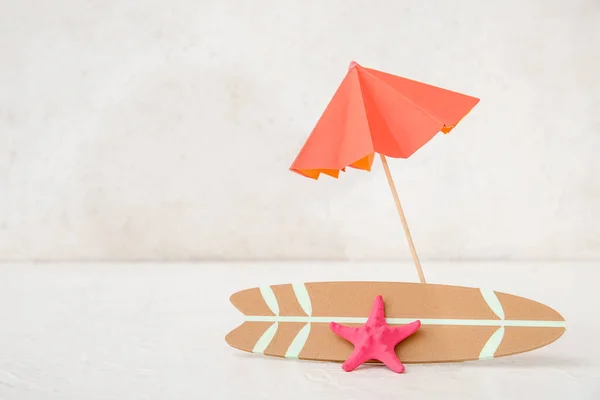 浅色背景的带伞和海星的迷你冲浪板 — 图库照片
