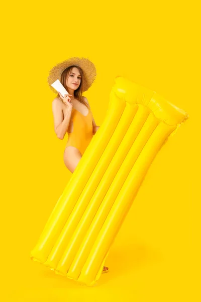 Junge Frau Mit Sonnencreme Und Aufblasbarer Matratze Auf Gelbem Hintergrund — Stockfoto