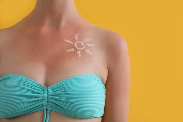 黄色の背景にクリームで作られた日焼け肌と太陽を持つアレルギーの若い女性 — ストック写真