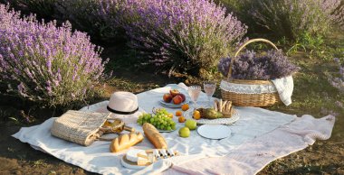 Lavanta çiçekli hasır sepet, tarlada romantik piknik için lezzetli yemek ve şarap.