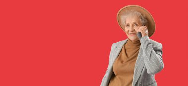 Kırmızı arkaplanda cep telefonuyla konuşan son sınıf öğrencisi.