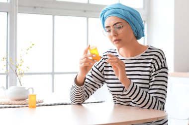 Kemoterapiden sonra genç bir kadın mutfaktaki masada oturan haplarla