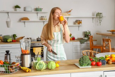 Mutfakta turuncu elbiseli genç bir kadın.