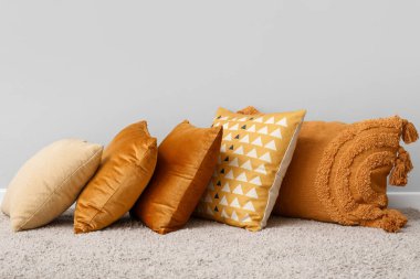 Halıda şık yastıklar, ışık duvarının yanında.