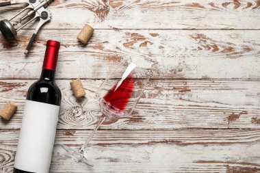 Hafif ahşap zemin üzerinde şişe ve bir bardak kırmızı şarap.