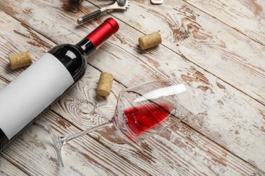 Hafif ahşap zemin üzerinde şişe ve bir bardak kırmızı şarap.