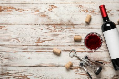 Hafif ahşap zemin üzerinde şişe ve bir bardak kırmızı şarap.