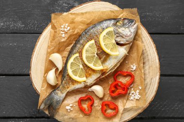 Koyu ahşap arka planda lezzetli ızgara dorado balıklı pano.