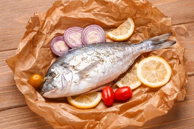 Limonlu çiğ dorado balığı ve ahşap arka planda sebze.