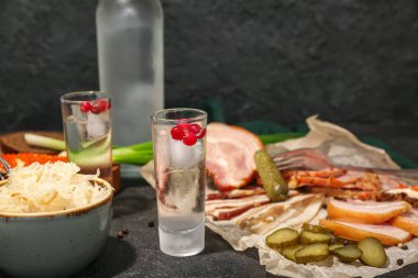 Soğuk votka ve siyah arka planda atıştırmalıklar.