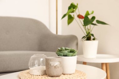 Mumlu hasır, seramik bardaklı ve kahve sehpasının üzerinde oturma odasındaki gri kanepenin yanında.