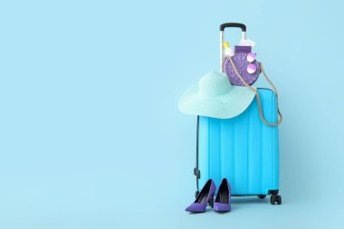 Pasaportlu bavul, yüksek topuklu ayakkabı ve mavi arka planda plaj aksesuarları. Seyahat kavramı