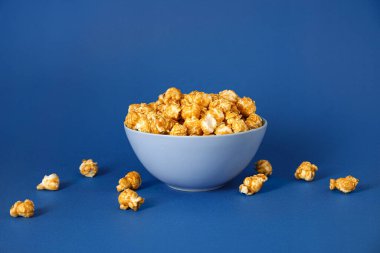 Mavi arka planda lezzetli patlamış mısır kasesi