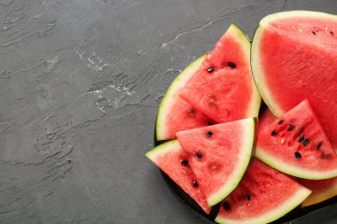 Siyah zemin üzerinde taze karpuz parçaları olan bir tabak.
