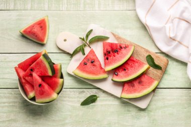 Yeşil ahşap zemin üzerinde taze karpuz parçaları olan yemek ve kâse.