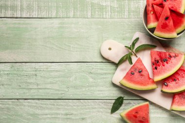 Yeşil ahşap zemin üzerinde taze karpuz parçaları olan yemek ve kâse.