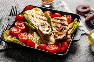 Arkaplanda lezzetli ızgara sebzeli fırın yemeği.