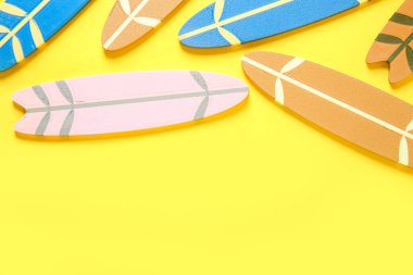 Sarı arka planda birçok farklı renkli mini sörf tahtaları