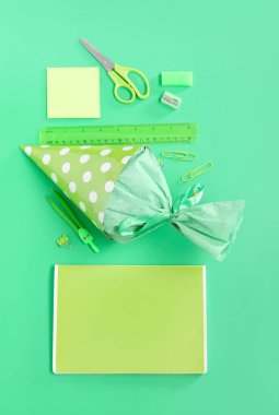 Yeşil arka planda farklı kırtasiye malzemesi olan okul konisi