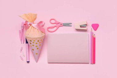 Okul konisi pembe arka planda farklı kırtasiye malzemesi ile