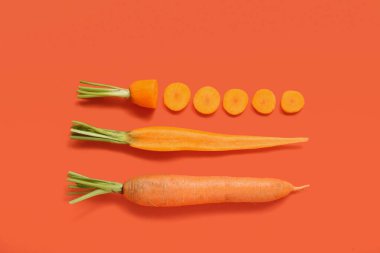 Turuncu arka planda taze havuç ve dilimler.