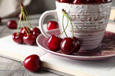Tatlı kirazlı bir tabak ve gri fayanslı bir fincan. Yakın plan.