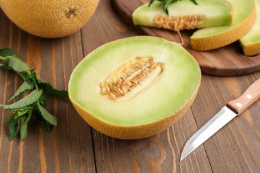 Tatlı kavunun yarısı ve ahşap zemin üzerinde parçalar