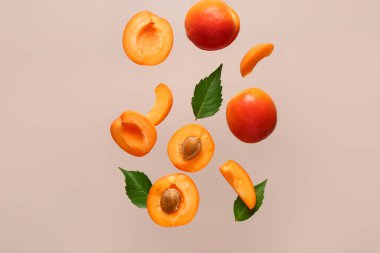 Bej arkaplanda taze kayısılar ve yapraklar uçuşuyor.