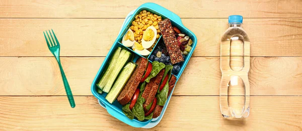 Lunchbox Met Lekker Eten Flesje Water Houten Ondergrond — Stockfoto