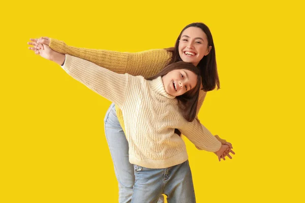 小さな女の子と彼女の母親で編んだセーターで黄色の背景 — ストック写真