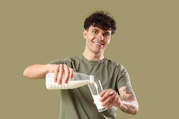 Young Man Pouring Milk Glass Green Background — Stock Photo, Image