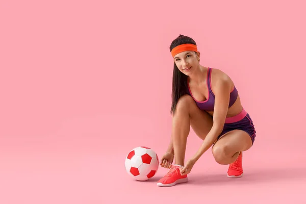 Sportovní Mladá Žena Fotbalové Míč Vázání Tkaničky Růžovém Pozadí — Stock fotografie