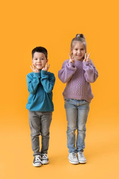 Crianças Bonitos Camisolas Malha Mostrando Gesto Vitória Fundo Amarelo — Fotografia de Stock