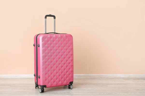 粉红手提箱靠近苍白的橙色墙壁 旅行概念 — 图库照片