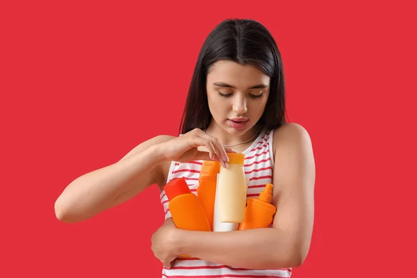 Молодая Женщина Бутылками Крема Загара Красном Фоне — стоковое фото