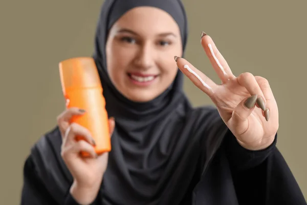 年轻的穆斯林妇女用防晒霜在绿色背景上表现出胜利的姿态 — 图库照片