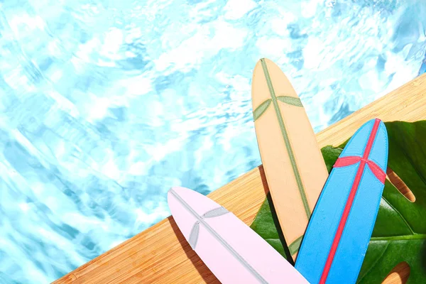 Yüzme Havuzunun Kenarında Palmiye Yaprağı Olan Farklı Mini Sörf Tahtaları — Stok fotoğraf