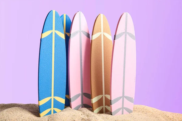 Verschiedene Mini Surfbretter Auf Sand Vor Fliederfarbenem Hintergrund — Stockfoto