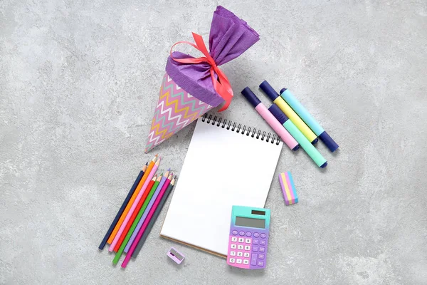 Blank notebook with purple school cone and different stationery on grunge grey background
