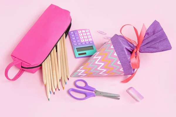 ピンクの背景に異なる文房具と紫の学校のコーン — ストック写真