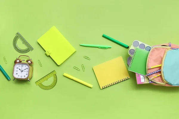 色彩艳丽的书包 绿色背景的笔记本 闹钟和铅笔 — 图库照片