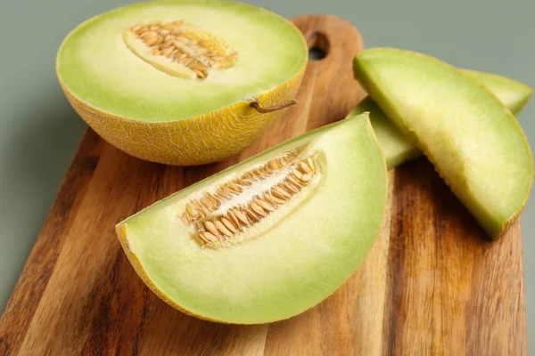 stock image Wooden board with half of sweet melon and pieces on grey background