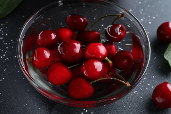 stock image Glass bowl with sweet cherries on black background