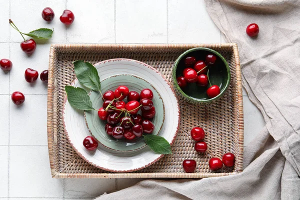 stock image Plate and bowl with sweet cherries on white tile background